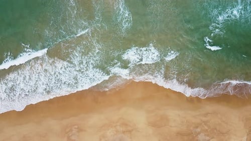 Aerial view of white sand beach and ocean wave. Zoom in.