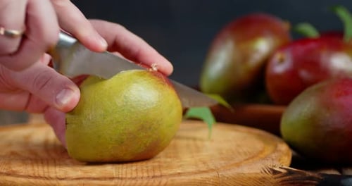 Cutting Fresh Mango with a Knife on Board