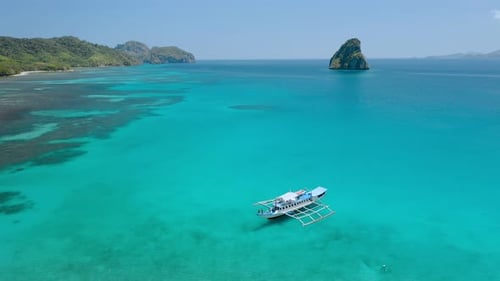 Aerial Drone View Circling Around Island Hopping Boat Moored in Shallow Water in Turquoise Blue