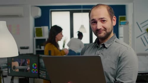 Man Smiling While Using Laptop in Modern Office