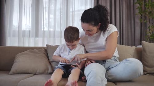 Woman and Child Enjoying Tablet Together on Couch