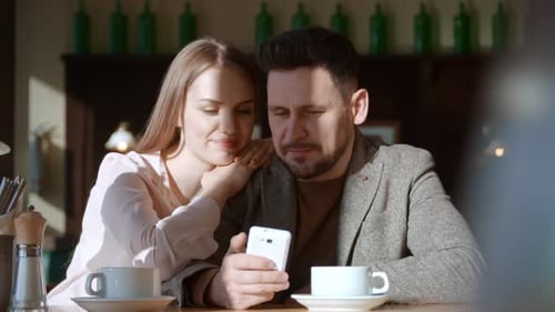 Loving Couple with Mobile Phone in Cafe