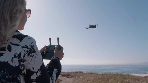 Woman Controls Drone on Ocean Coastline