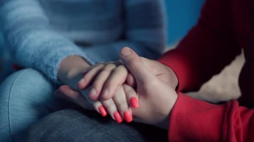 Junger Mann hält die Handfläche einer Frau in seinem Unterstützungs- und Pflegekonzept, Nahaufnahme