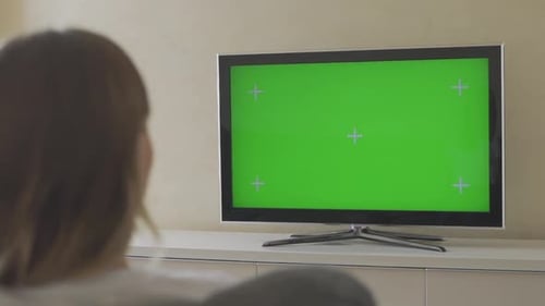 Woman in the Sitting on the Sofa in the Living Room and Watching TV with Green Screen, Then Changing