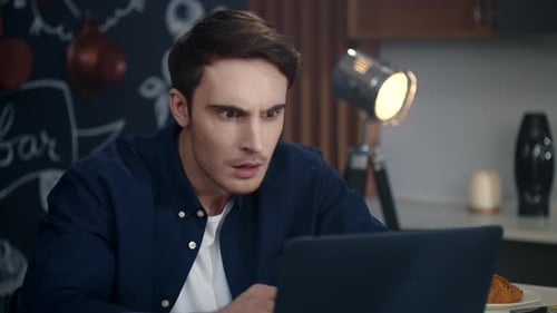 Man Looks at Laptop with Shocked, Worried Expression