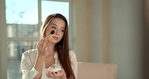 Beautiful Girl Doing Makeup with a Brush in Studio