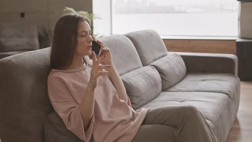 Woman Chatting on Smartphone While Relaxing on Couch