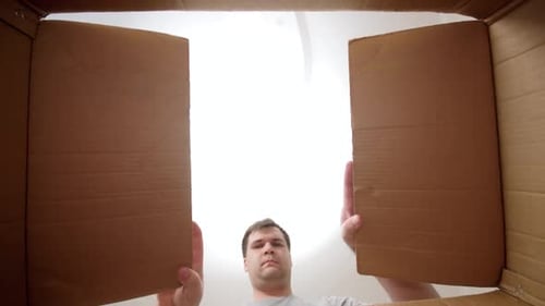 Le point de vue d'un jeune homme ouvre une boîte en carton et s'étonne