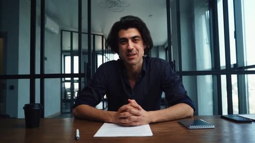 Young Adult Man Explaining at Desk in Office