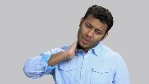 Homme triste à la peau foncée touchant son cou ressentant de la douleur