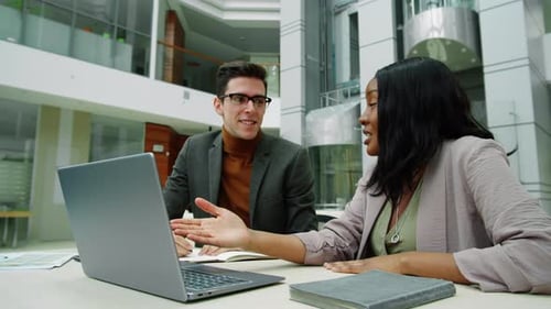 Multiethnic Coworkers Using Laptop and Talking in Office Center