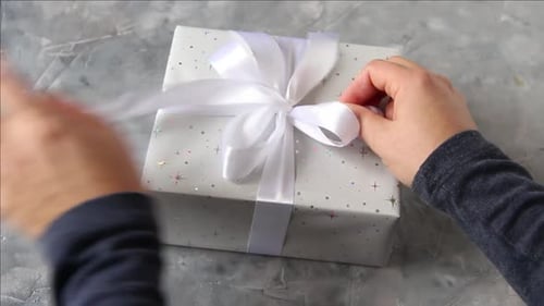 Hands Tying Ribbon on a Birthday Gift