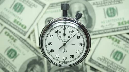 Stopwatch Running Over US Hundred Dollar Bills