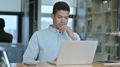 Young Adult Typing on Laptop in Office