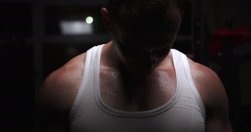 A man in the gym breathes deeply after exercise, his body is covered with beads of sweat