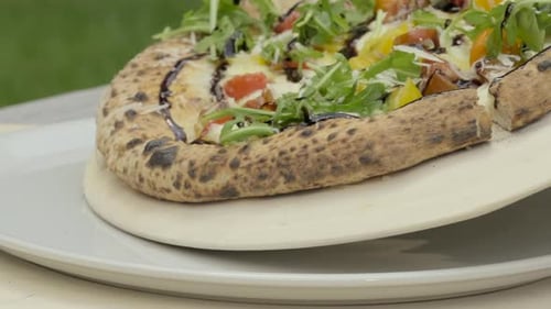 Chef Slides Wood Fired Pizza With Balsamic Arugula And Tomatoes Onto Plate