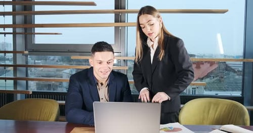 Portrait of a Man and a Woman Discussing Work with Notebook in the Brightly Lit Modern Office