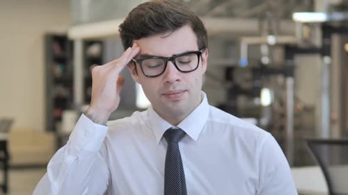 Stressed Young Adult Rubbing Temples at Office