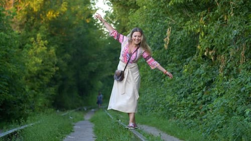 Glückliche junge Frau balanciert auf Bahngleisen