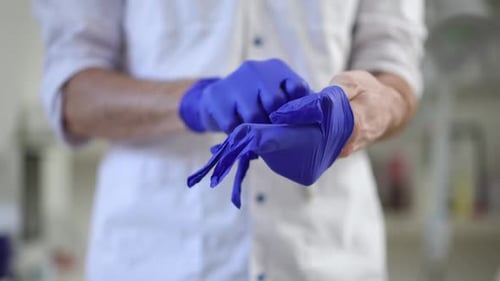 Healthcare Worker Puts on Protective Blue Gloves