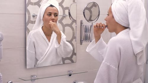 Woman in Robe Brushing Teeth in Bathroom