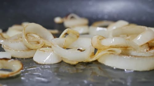 Stir Fried Onion Rings with a Culinary Spatula in a Hot Frying Pan Dolly Shot