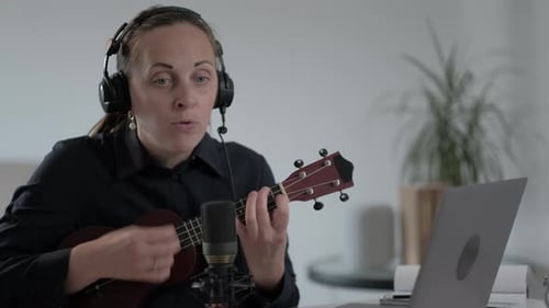 Woman Playing Ukulele and Singing at Desk