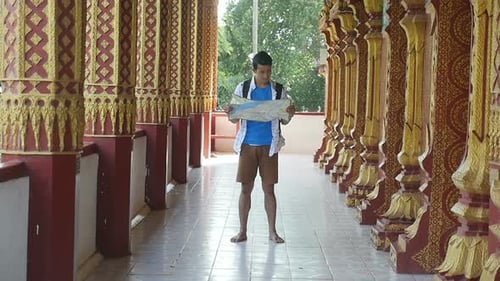 Young Adult Stands Barefoot Reading Map