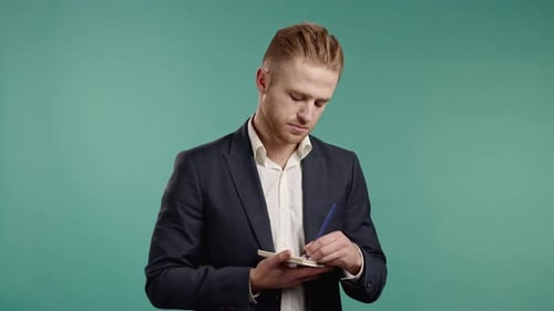 Linkshänder junger Geschäftsmann macht sich Notizen in Planner Guy Holding Pen reflektiert Pläne