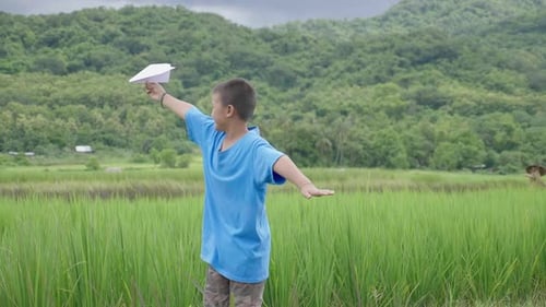 Smiling Boy Playing With Paper Airplane in Field