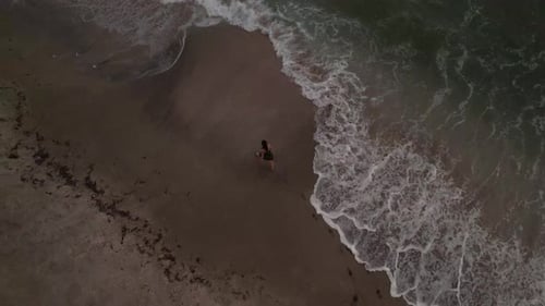 Woman Walking on a Beach from Aerial View
