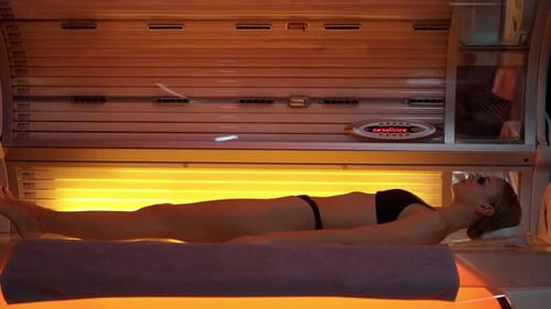 Spa Treatments Young Female Sunbathing in a Solarium Warm Light
