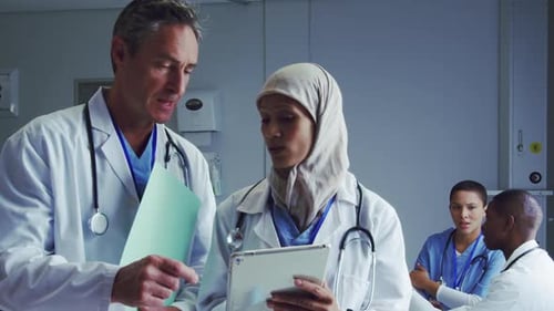 Front view of Multi-ethnic doctors discussing over digital tablet in hospital