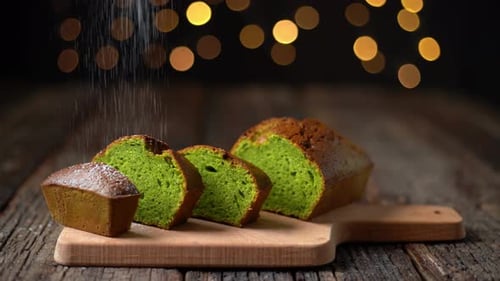 Pan navideño Stollen hecho de espirulina y pistachos espolvoreado con polvo para las fiestas