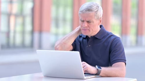 Man Working on Laptop Rubs Neck in Pain