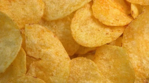 Crispy potato chips rotating in macro. Golden fried potatoes close up. Potato snack for unhealthy