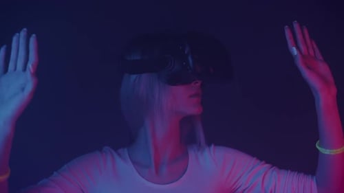 Close Up of Young Girl in Virtual Reality Glasses Moves Hands at Futuristic Neon Lights Background