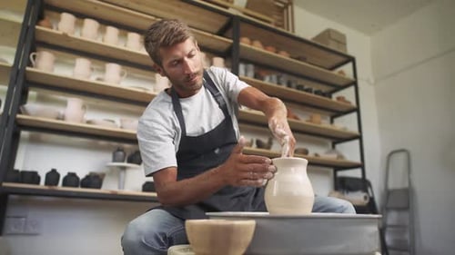 Man Potter stellt einen Krug aus Ton her. Handwerkliche Herstellung von handgefertigtem Geschirr, Töpferwerkstatt