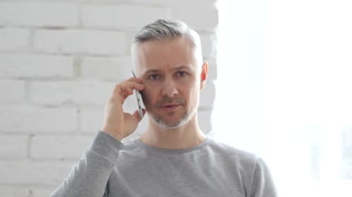 Hombre de mediana edad hablando por teléfono, negociación en el móvil
