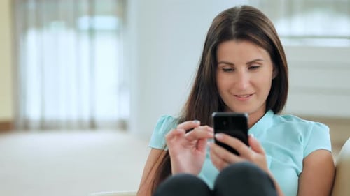 Woman Using Smartphone Relaxing on Couch at Home