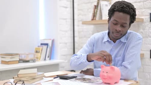 Afrikanischer Mann legt Geld ins Sparschwein