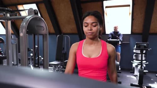 African American woman walking on treadmill in gym