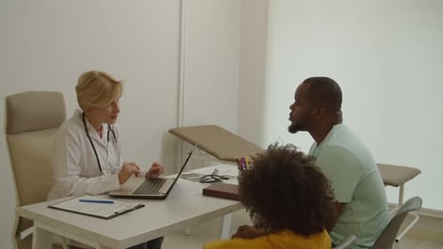 Doctor Consults with Father and Child in Office