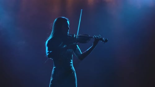 Violinist plays instrument with blue lights on stage