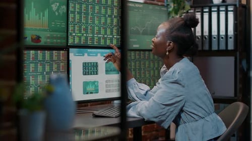 Woman Analyzing Financial Data on Multiple Screens