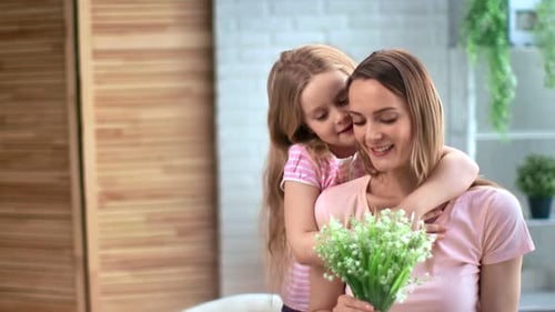 Child Hugging Mother with Flowers Inside Home