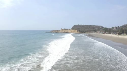 Flying over the shoreline of the Pacific ocean with small waves