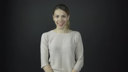 Woman Smiling and Posing Against Dark Background