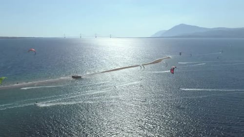 Aerial view of big group kitesurfing close to the shore.